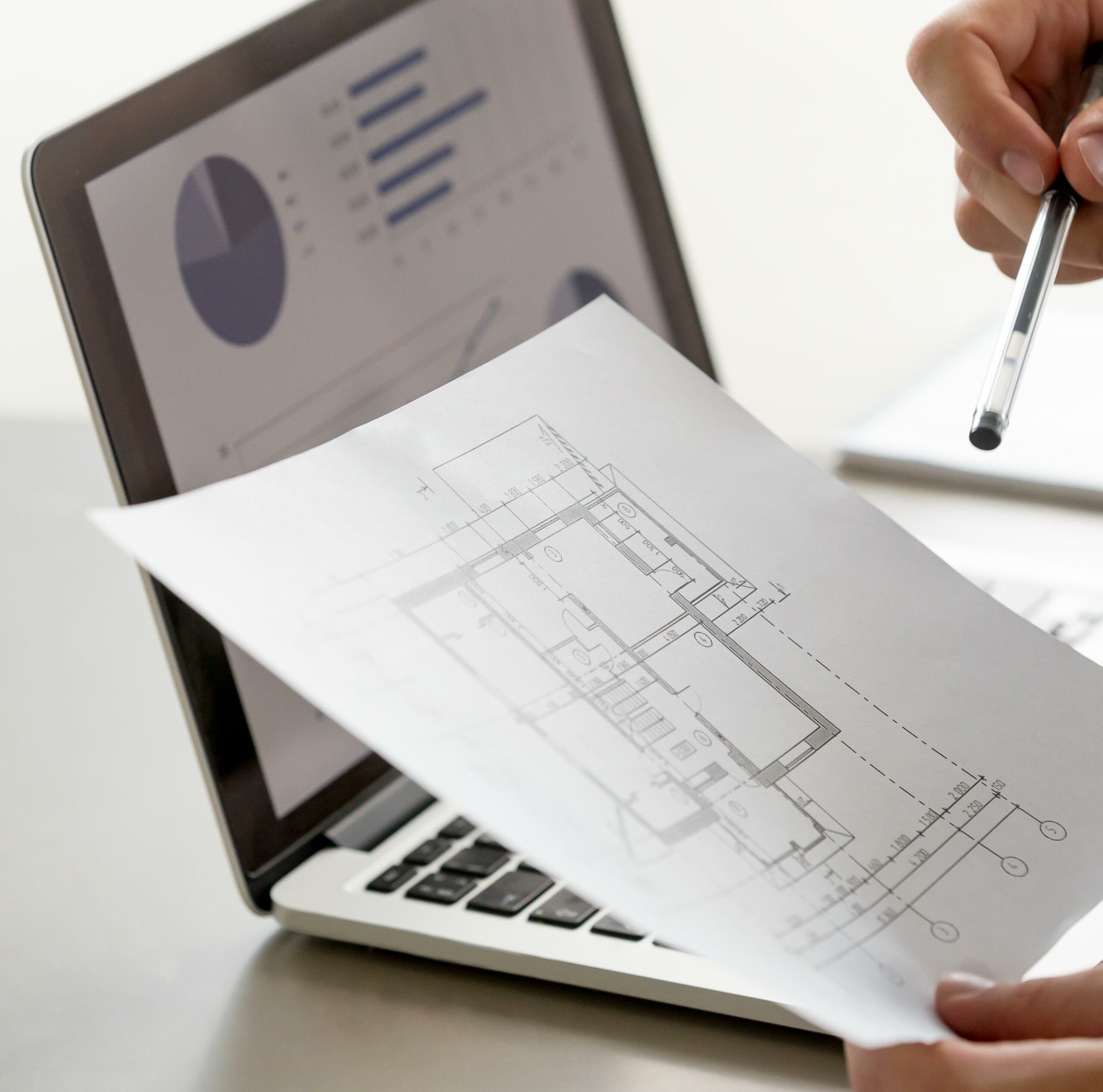 Male hand holding project plan, statistics on screen, close up